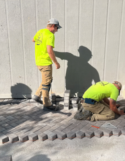Workers installing pavers in a patio area by Weadickbros Landscape Design & Build
