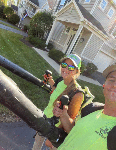 Team members holding leaf blowers while smiling, by Weadickbros Lawn & Landscape.