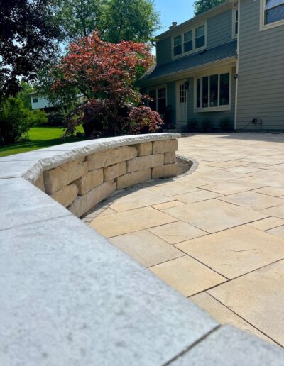 Elegant stone patio with a curved wall by Weadickbros Landscape Design & Build.
